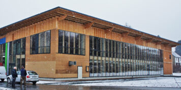 Kontakt - Schlosser und Schlosser - Tischlerei Holzbau Treppenbau in Oelsnitz Außenansicht des Firmengebäudes der Holzwelten Schlosser GmbH in Oelsnitz im Winter mit Holzfassade und Glasfront