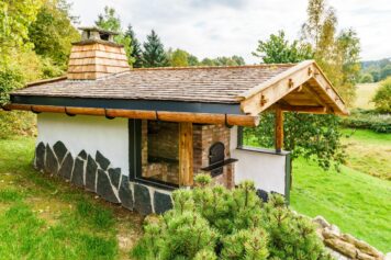 Traditionelle Handwerkskunst aus Oelsnitz – natürlich, nachhaltig und detailverliebt Außenansicht eines Nebengebäudes mit Dachstuhl aus regionalem Altholz, Lärchenschindel-Dacheindeckung und handgearbeiteten Dachrinnen, gefertigt von der Tischlerei Holzwelten Schlosser GmbH in Oelsnitz.