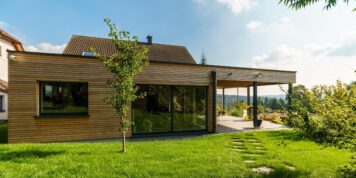 Naturbelassene Lärcheleisten mit Hinterlüftung und Holzfaserdämmung – handwerklich präzise umgesetzt von Holzwelten Schlosser GmbH Moderne hinterlüftete Holzfassade aus naturbelassenen Lärche-Rhombusleisten mit großen Fensterflächen, umgesetzt von der Tischlerei Holzwelten Schlosser GmbH aus Oelsnitz.