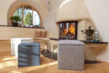 Handgefertigter Sitzwürfel mit Stauraum | Holzwelten Schlosser, Oelsnitz Climacube Sitzwürfel aus 100% Schafwollvlies vor gemütlichem Kamin, handgefertigt von Holzwelten Schlosser in Oelsnitz.