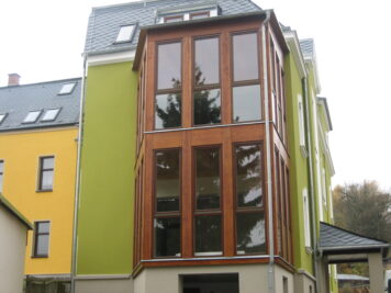 Langlebige Konstruktion mit wetterfester Lärchenholz-Verkleidung – gefertigt von Holzwelten Schlosser GmbH, Oelsnitz Zweigeschossiger Wintergarten aus Lärchenholz mit großflächiger Verglasung an einem Wohngebäude, gefertigt von der Tischlerei Holzwelten Schlosser GmbH in Oelsnitz