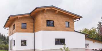 Handwerk von der Tischlerei Holzwelten Schlosser GmbH in Oelsnitz Wohnhaus mit moderner Kombifassade aus Lärchenholz und weißem Putz, gefertigt von der Tischlerei Holzwelten Schlosser GmbH