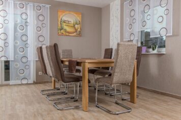 Handgefertigt von der Tischlerei Holzwelten Schlosser GmbH in Oelsnitz Zeitloser Esstisch aus massiver Eiche mit acht gepolsterten Freischwinger-Stühlen in einem Esszimmer mit hellem Holzboden