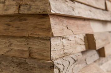Individuelle Oberflächengestaltung aus historischem Holz – gefertigt von Holzwelten Schlosser GmbH, Oelsnitz Nahaufnahme einer strukturierten Altholz-Wandverkleidung aus massiven, unregelmäßig aufbereiteten Holzlamellen in verschiedenen Naturtönen.