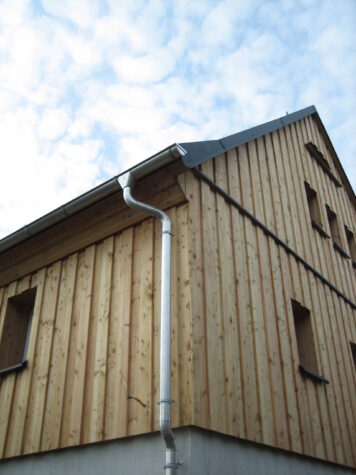 Natürlich vertäfelte Holzfassade mit handwerklich ausgeführter Detailgestaltung Wohnhaus mit vertikaler Holzfassade und modern gedecktem Dach, gefertigt von der Tischlerei Holzwelten Schlosser in Oelsnitz