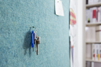 Akustik, Raumklima und Organisation – natürlich vereint Türkises Climapaneel aus Schafwollvlies, genutzt als Pinnwand mit Zetteln und einer Kinderzeichnung, handgefertigt von Holzwelten Schlosser in Oelsnitz.